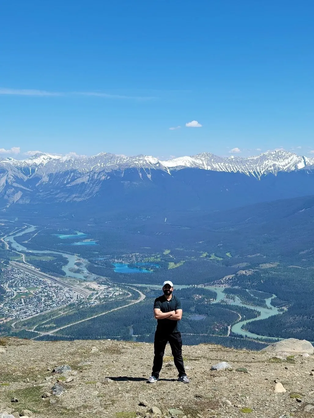 Standing on a rocky summit above the town of Jasper, Alberta, with the valley and snow-capped Rockies behind